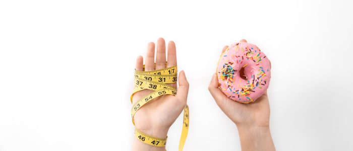 Hands hold donut and measuring tape on white, isolated, copy space.